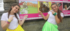 Girls pointing to Honk Production Sign outside Hawkswell